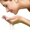 Beautiful woman refreshing her face with water